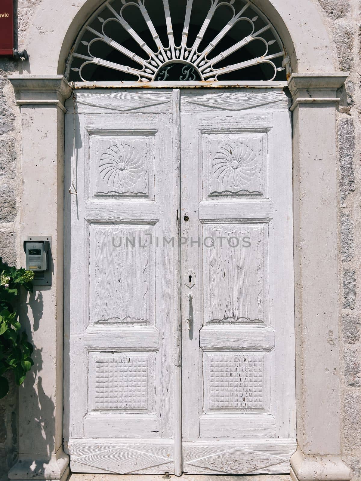 White wooden door with an arched top in the stone wall of an ancient building. High quality photo
