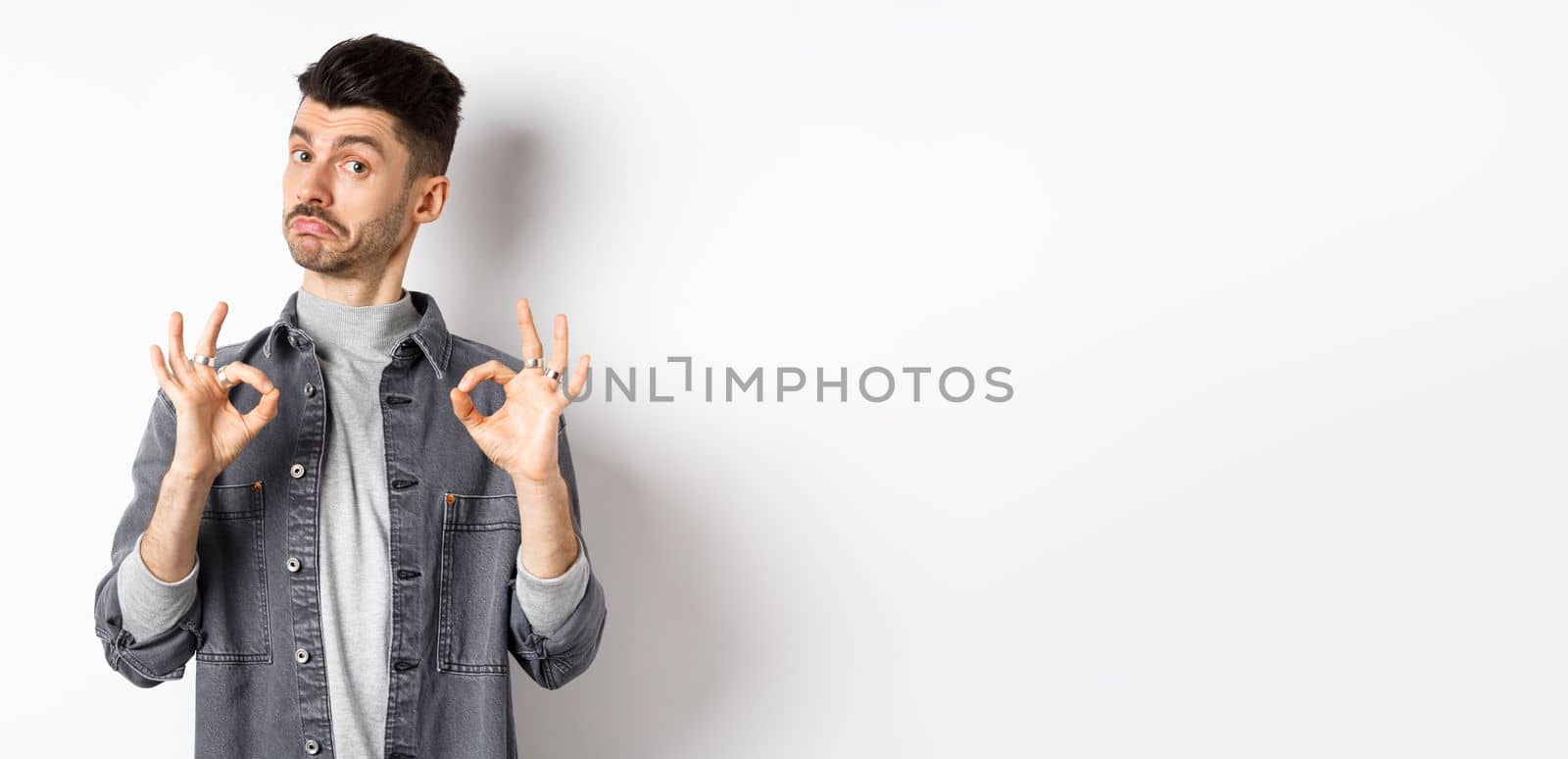 Not bad. Impressed handsome guy nod in approval, showing okay signs to make compliment, praise good work, like result, standing on white background.