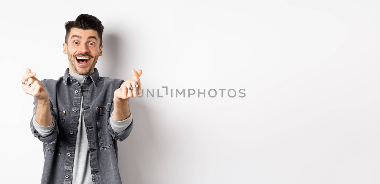 Excited romantic man showing hand hearts and smiling at camera, express love and affection, standing on white background by Benzoix