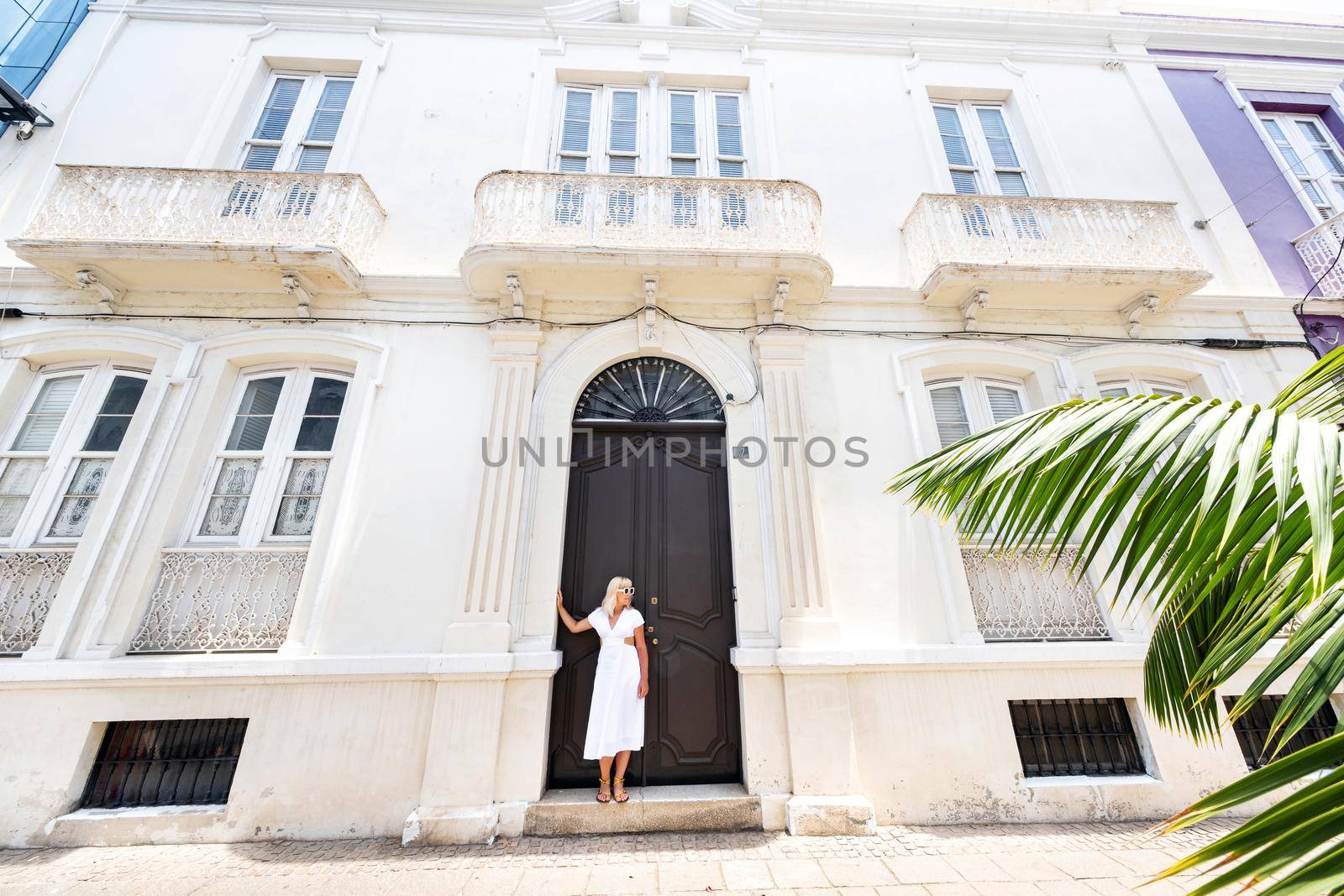 Tenerife, Canary Islands, Spain. A girl in a white dress stands against the wall of a house in Santa Cruz de Tenerife. by Lobachad