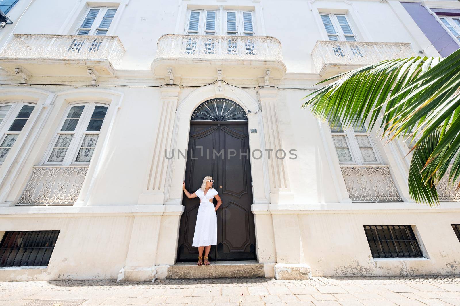 Tenerife, Canary Islands, Spain. A girl in a white dress stands against the wall of a house in Santa Cruz de Tenerife. by Lobachad