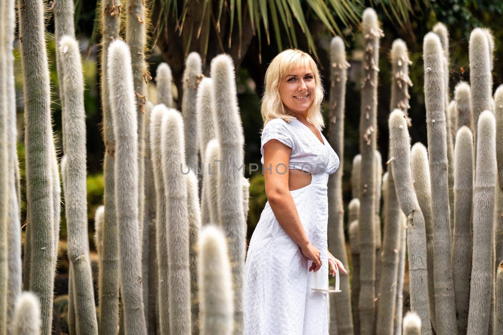 A girl in a white dress on the background of huge cacti on the island of Tenerife.Spain by Lobachad