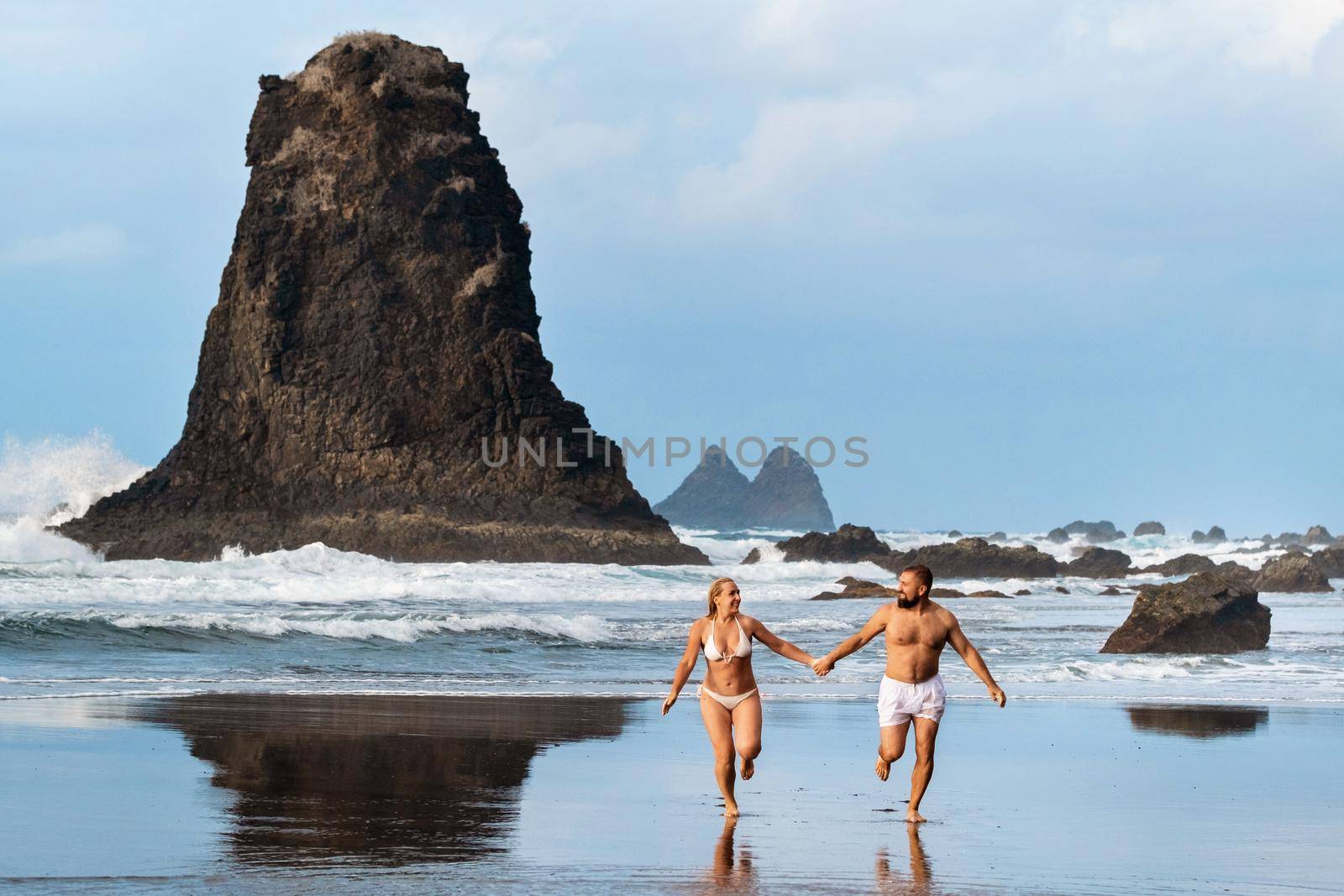 A couple of lovers on the sandy beach of Benijo on the island of Tenerife.Spain by Lobachad