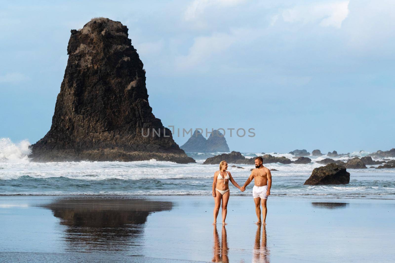 A couple of lovers on the sandy beach of Benijo on the island of Tenerife.Spain .