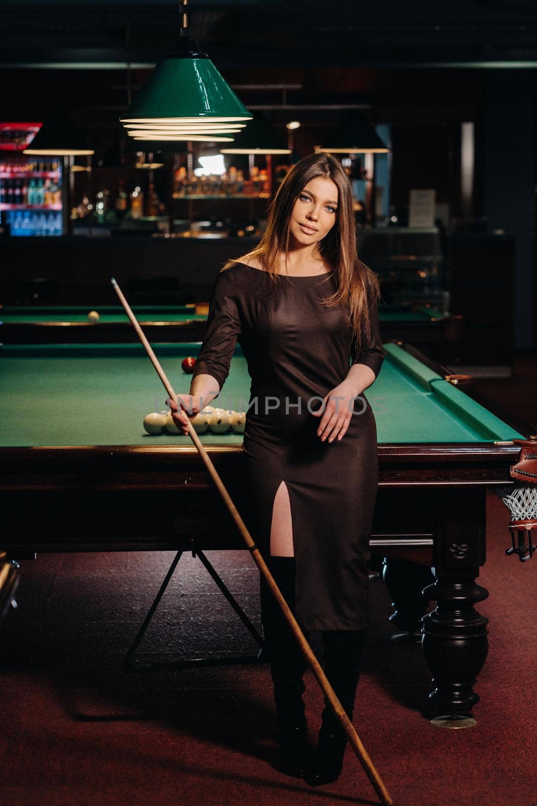 A girl in a hat in a billiard club with a cue in her hands.Pool Game.