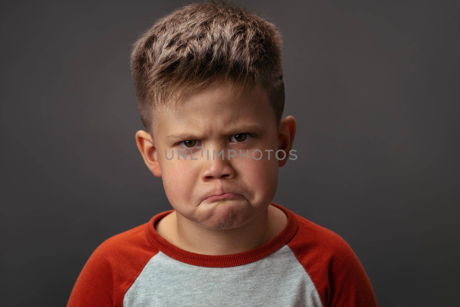 Preschool boy expresses sad emotions. Conflict concept. Close up portrait.