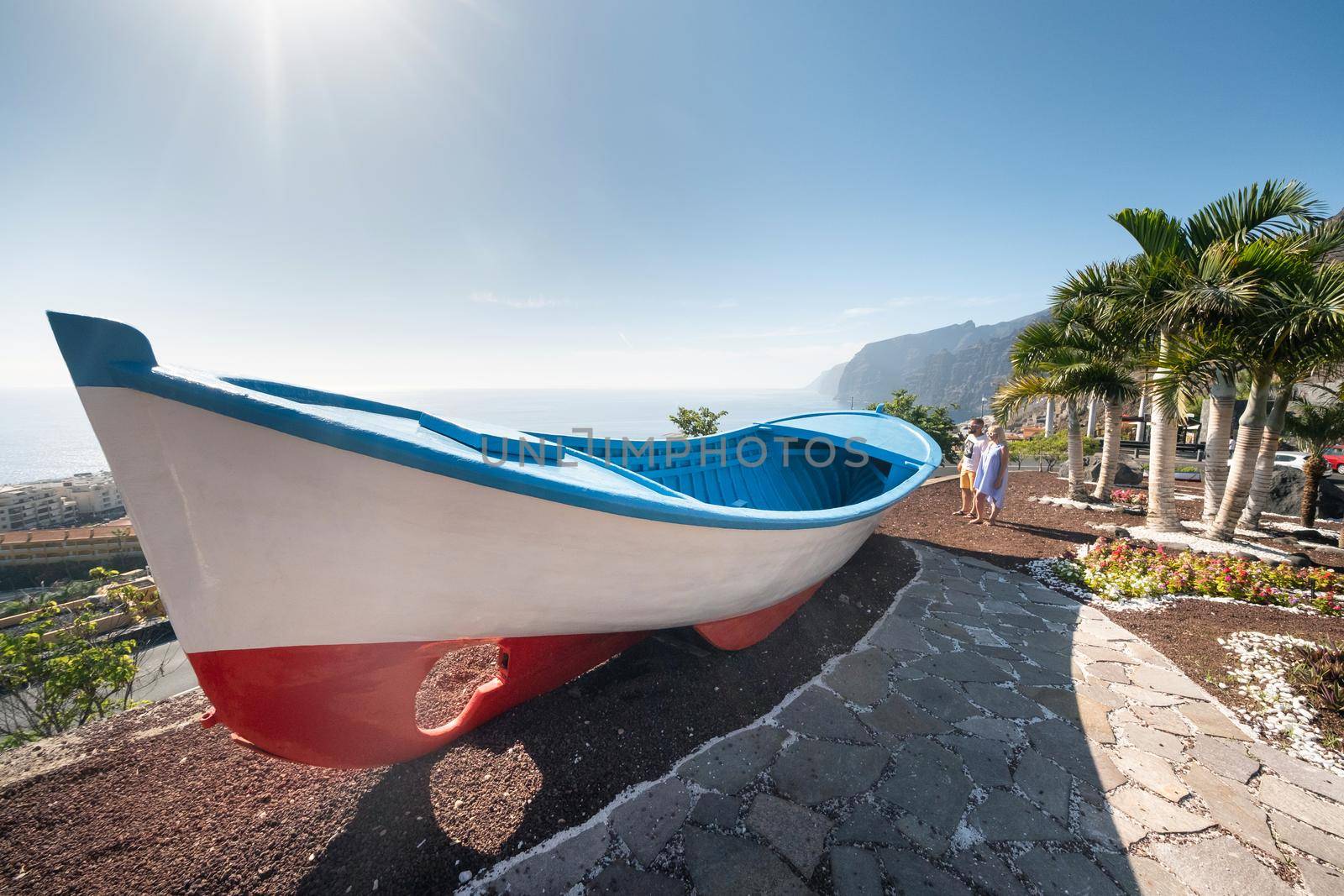 a couple of lovers at a huge boat, near the beach at the cliffs of Acantilados de Los Gigantes, Tenerife, Spain. by Lobachad