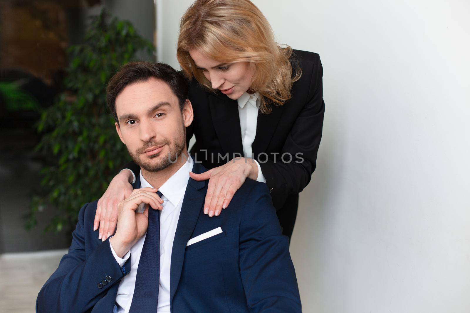 Female office worker seduces to male boss. Young woman stroking male shoulders. Women empowerment concept. Feminism concept. Copy space by LipikStockMedia