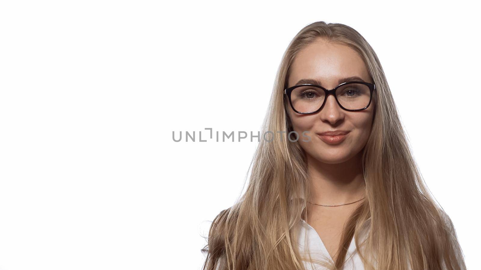 Beautiful girl in eye glasses with long straight blond hair looking at the camera wearing white medical uniform isolated on white background.