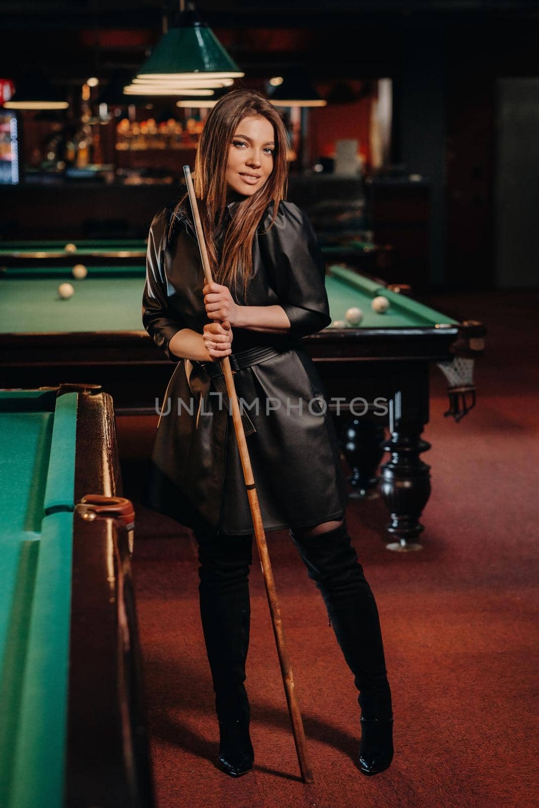 A girl with a cue in her hands is standing in a billiard club.Russian billiards.