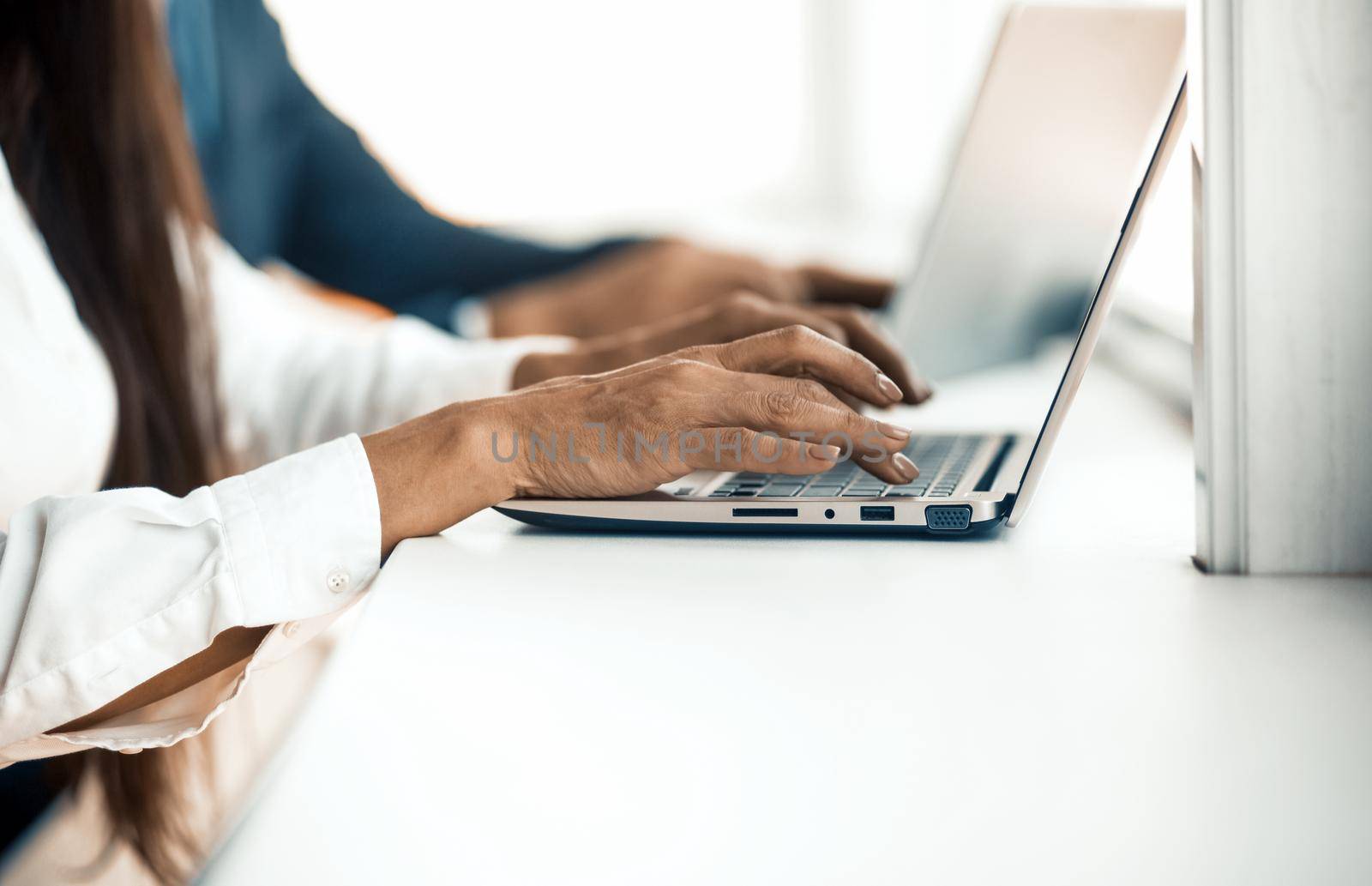 Businesspeople typing on laptop keyboard. Close up of Caucasian female hands working on computer at office desk. Copy space at bottom of image.