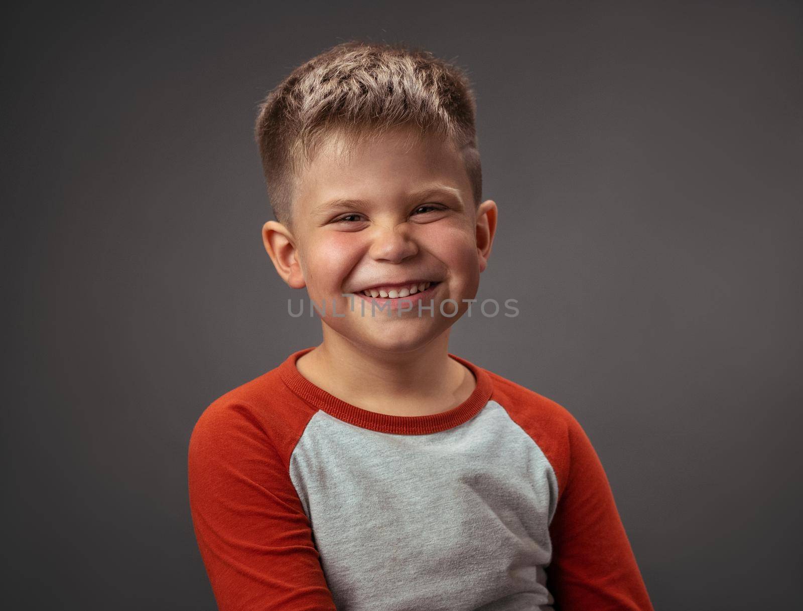 Happy preschool boy expresses joy. Smiling broadly child cut out on gray. Studio portrait. Emotions concept by LipikStockMedia