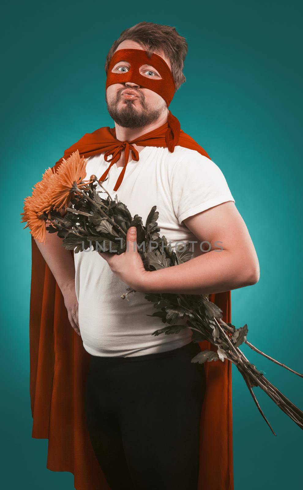 Super hero in love with a bouquet of flowers for his lover. Man in a Superhero costume holding a bouquet of chrysanthemums folded his lips for a kiss by LipikStockMedia