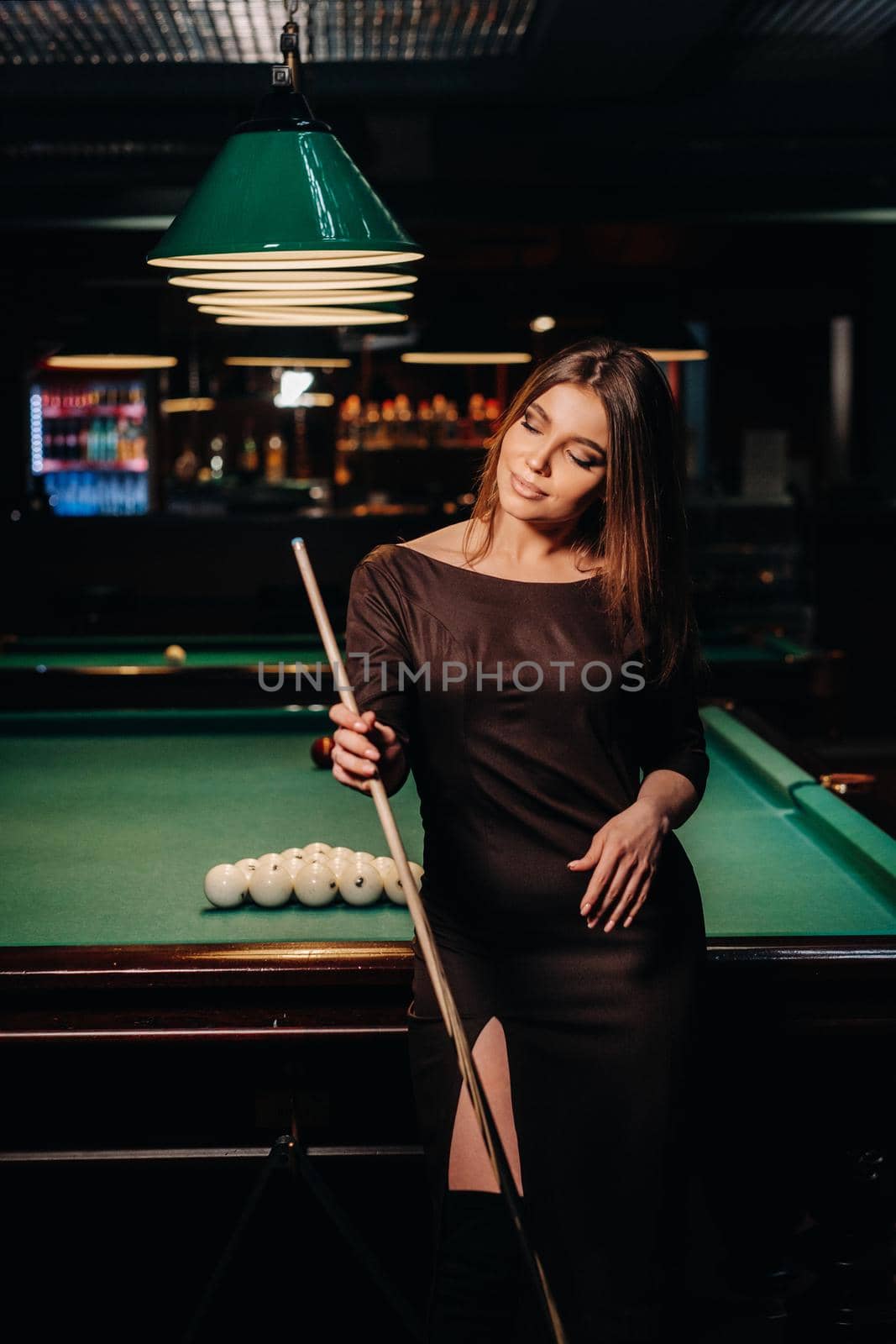 A girl in a hat in a billiard club with a cue in her hands.Pool Game by Lobachad