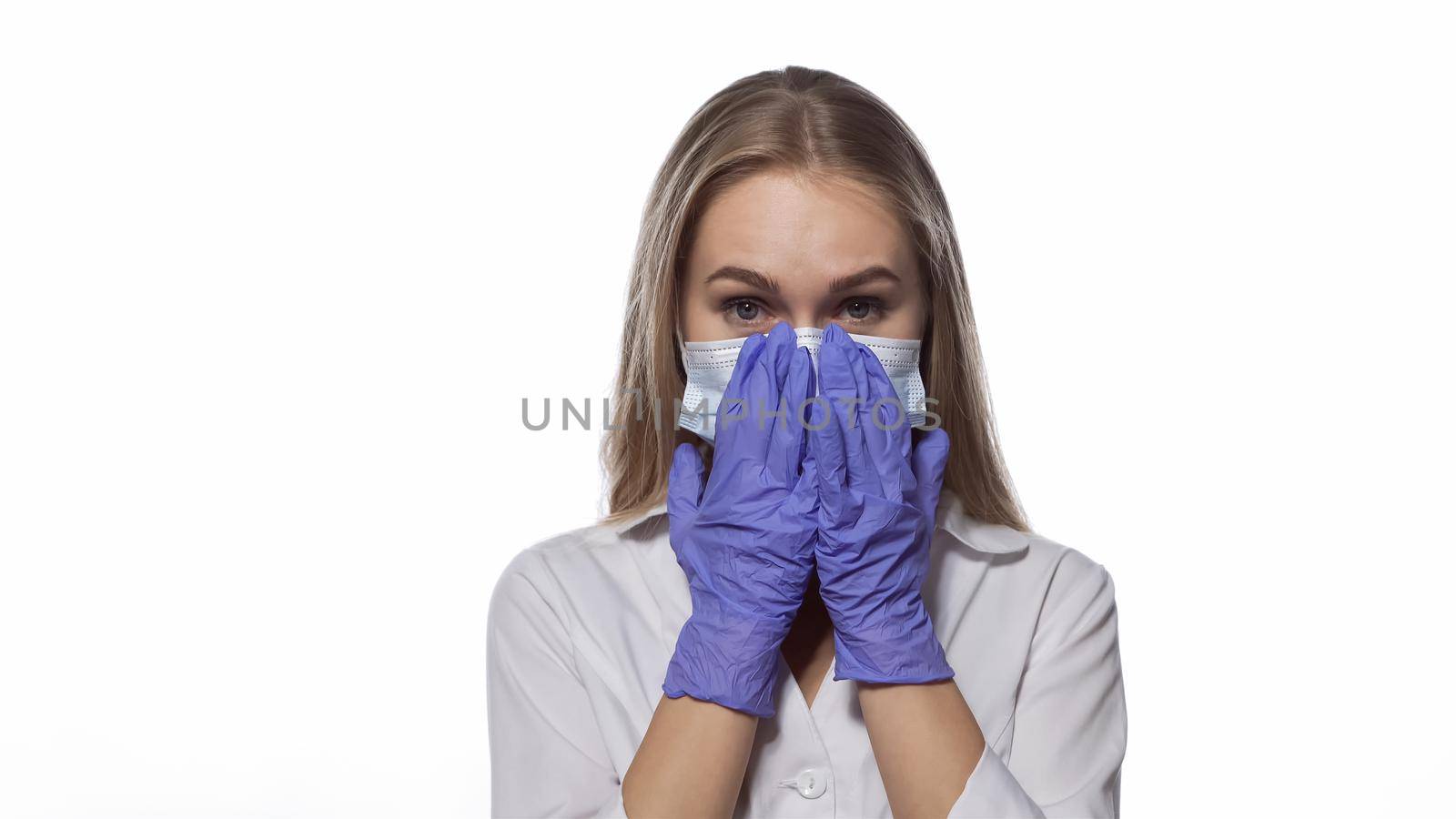 Correcting medical face mask young nurse with long straight hair looking at the camera wearing white medical uniform isolated on white background.