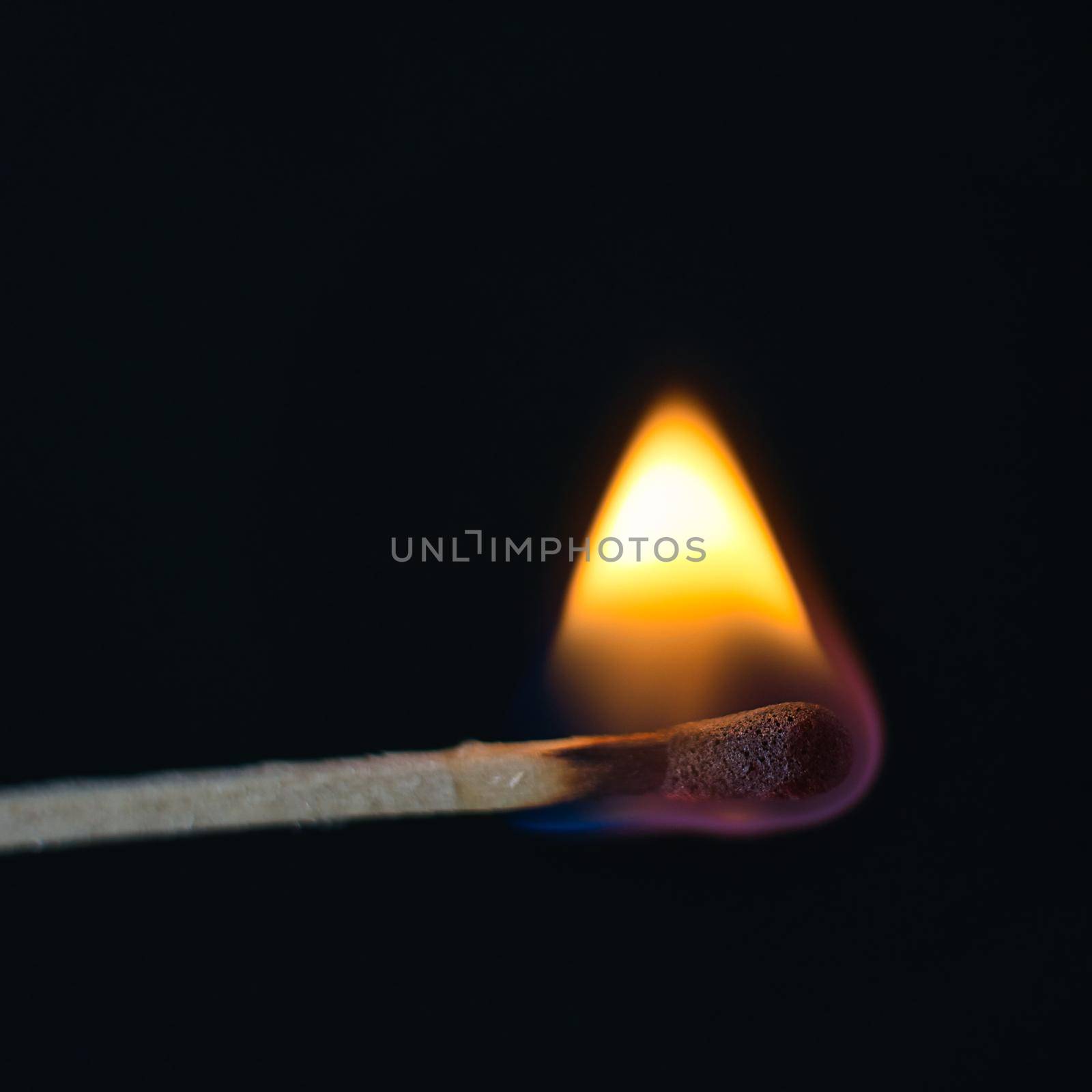 A selective focus of a match on fire on black background