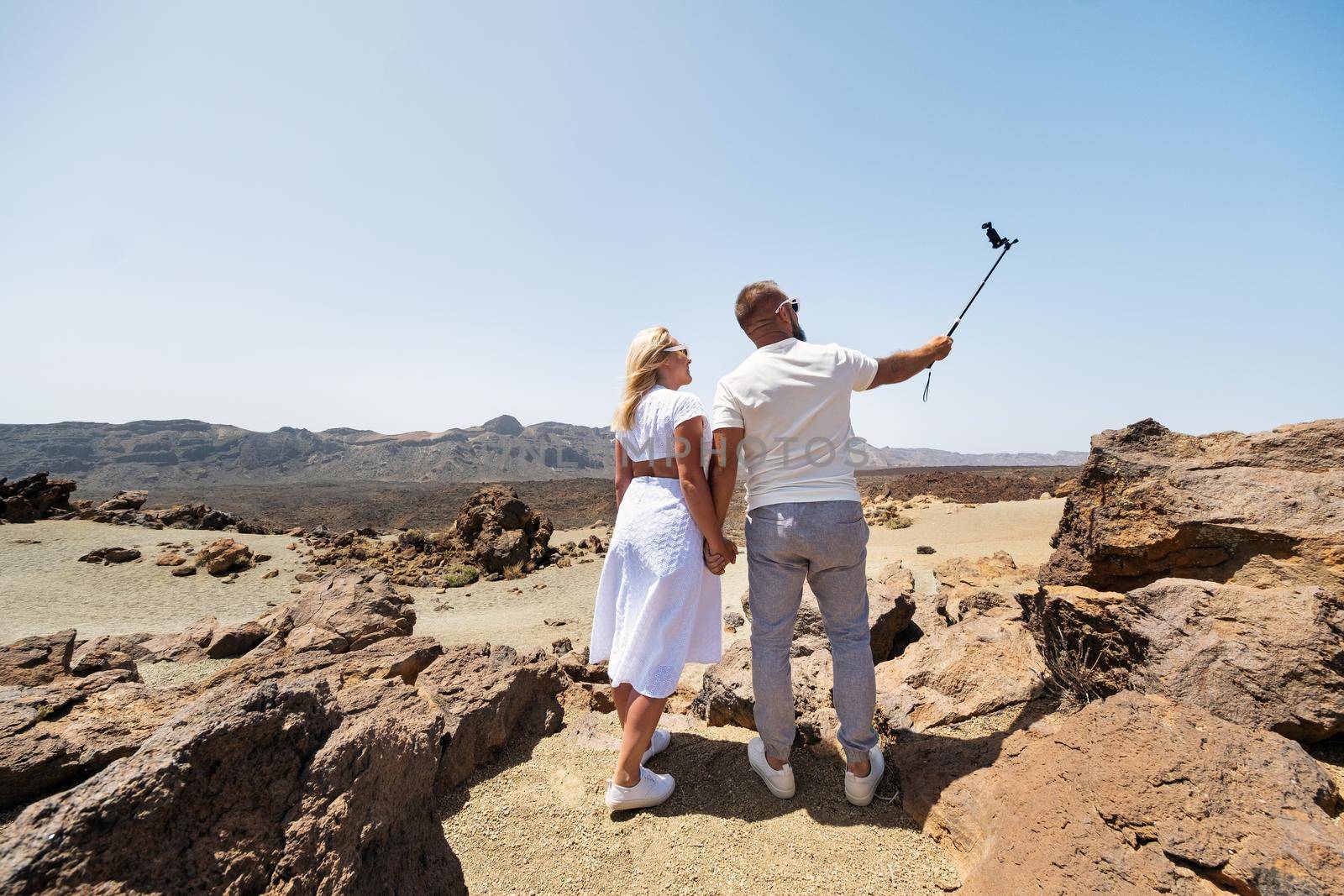 a stylish woman takes a selfie in the crater of the Teide volcano. Desert landscape in Tenerife. Teide National Park. Desert crater of the Teide volcano. Tenerife, Canary Islands.
