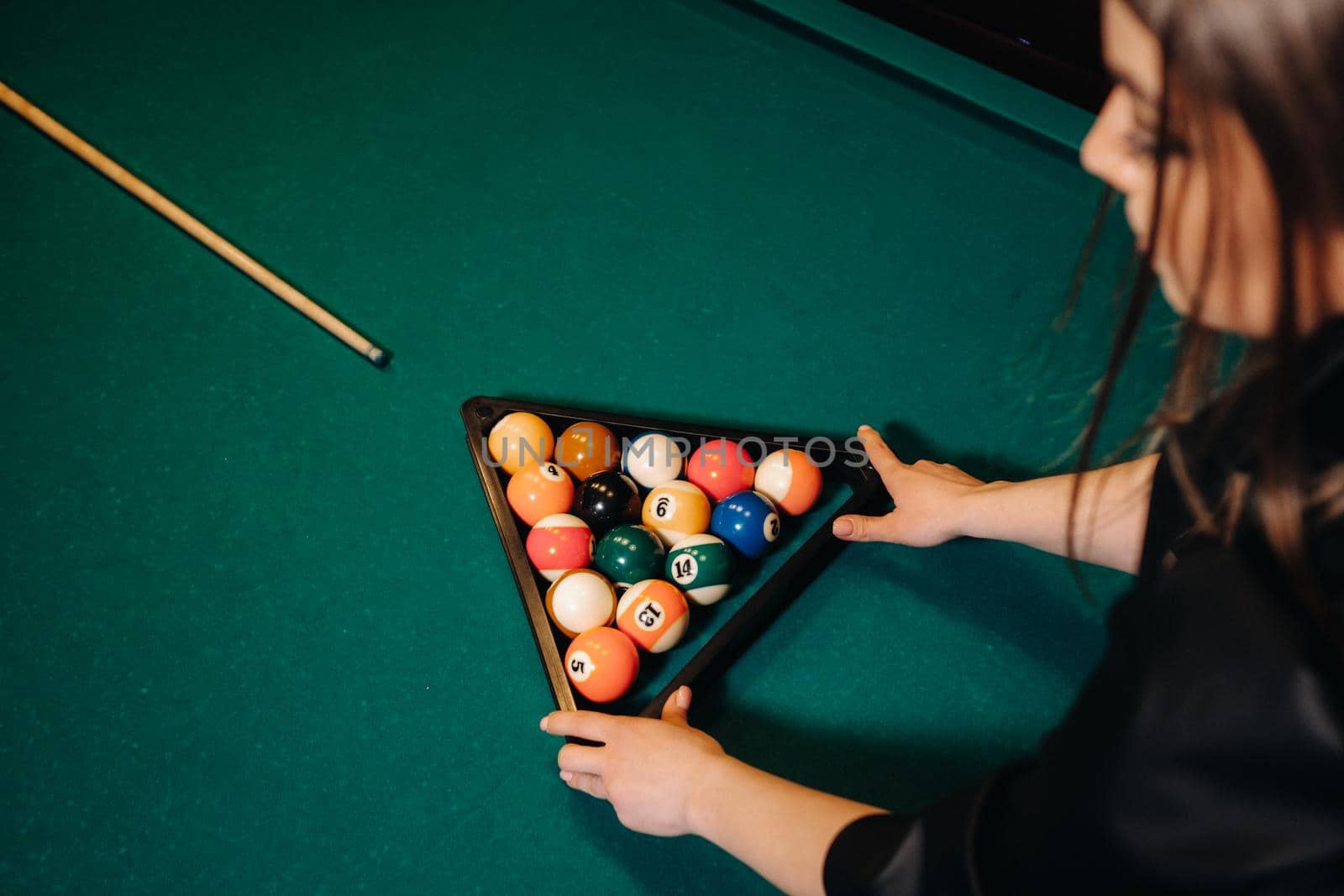 The girl puts out billiard balls to start the game in the billiard club .Playing pool.