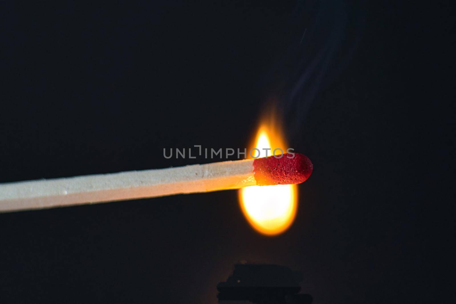 A selective focus of a match on fire on black background