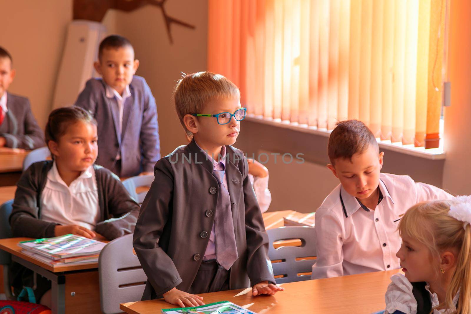 The first grader stands at the desk and answers the teacher's question. Moscow, Russia, September 2, 2019