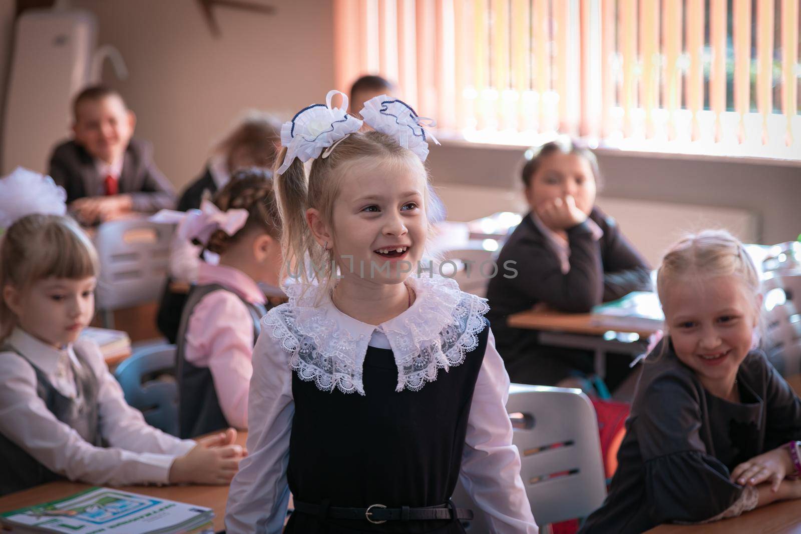 The first grader stands at the desk and answers the teacher's question. Moscow, Russia, September 2, 2019