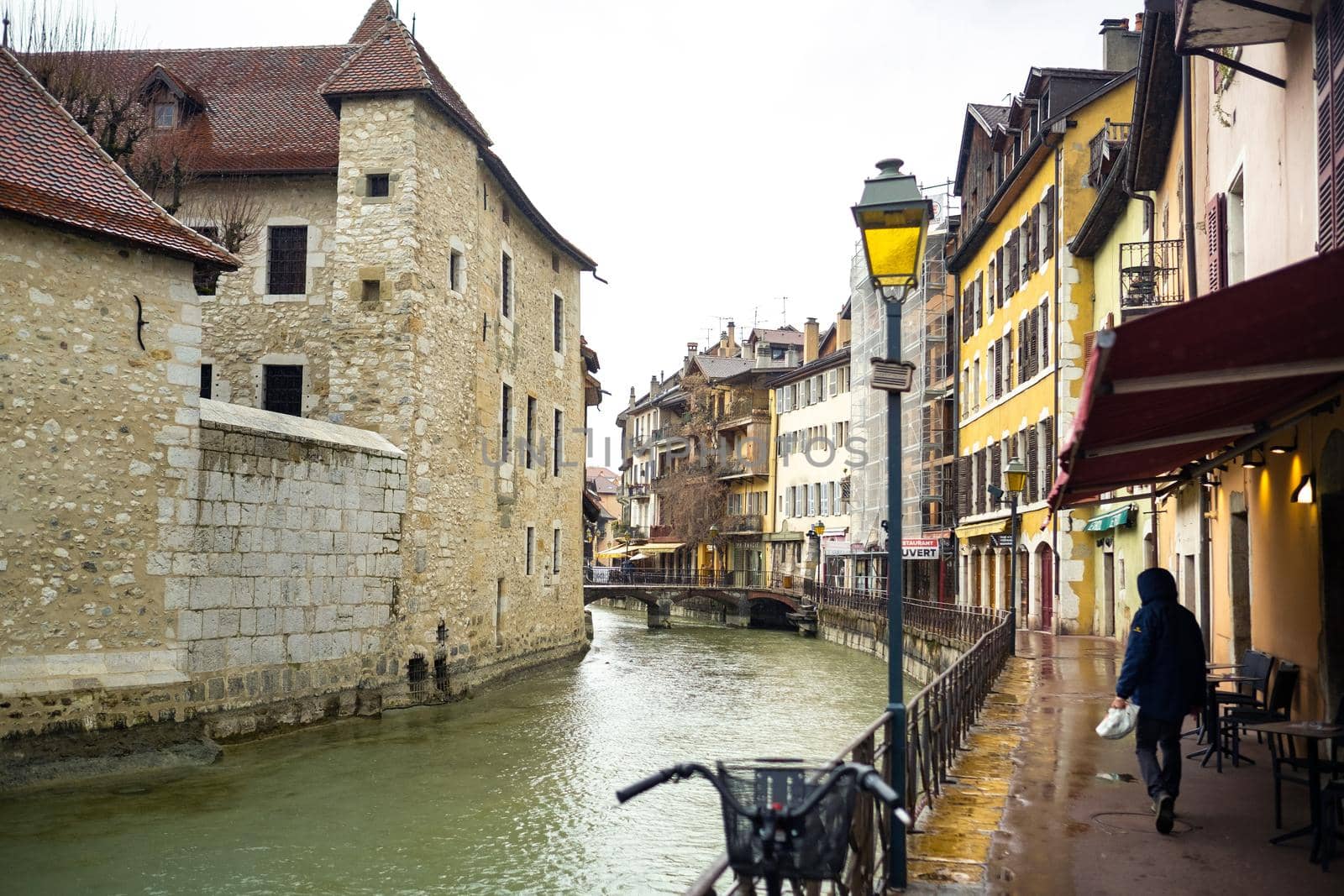 ANNECY, FRANCE-APRIL 3, 2019: The Tioux River embankment in the Old Town, surrounding a medieval palace located in the middle of the river-the Ile Palace on a rainy day by Lobachad