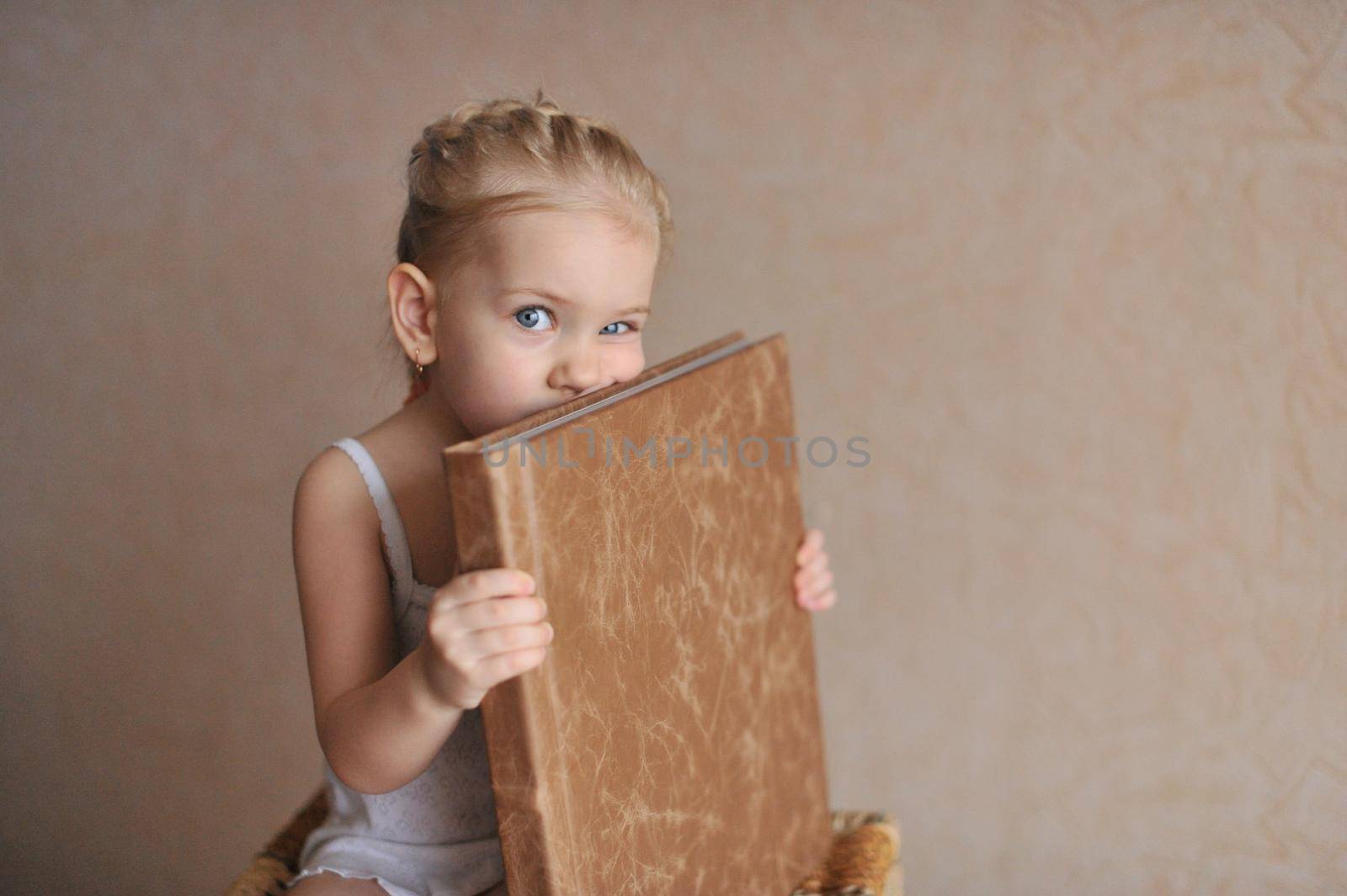 a little girl is holding a photo book in natural brown leather