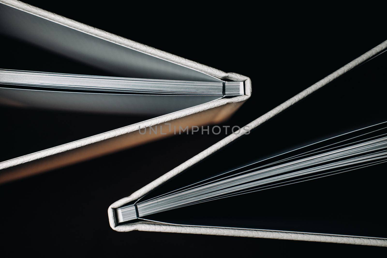 Composition of photo books in natural white leather of different sizes. The white paper on a dark background
