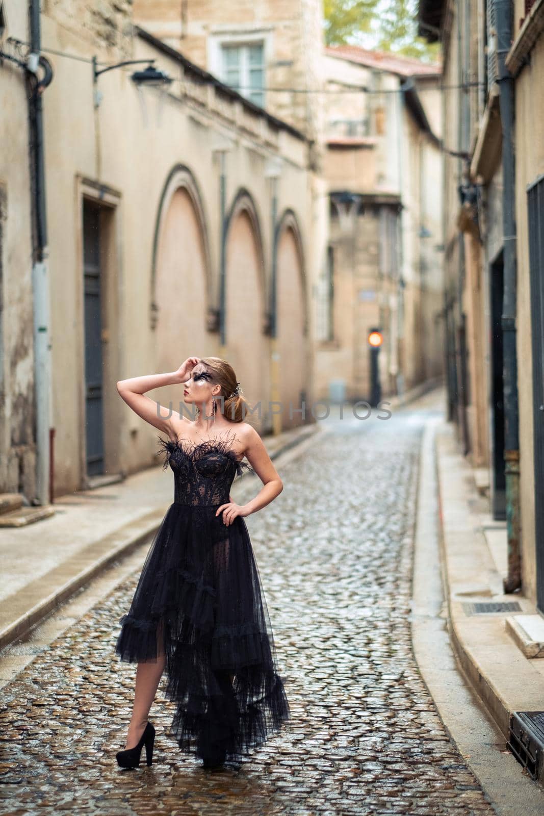 A stylish bride in a black wedding dress in the ancient French city of Avignon. A model in a black dress.