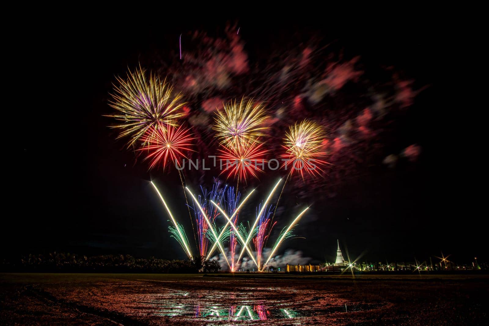 Huge, colorful fireworks over the rice fields at dusk.