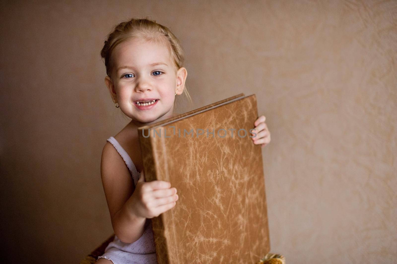 a little girl is holding a photo book in natural brown leather. by Lobachad