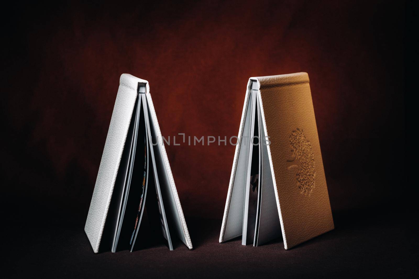 Composition of photo books in natural white leather of different sizes. The white paper on a dark background