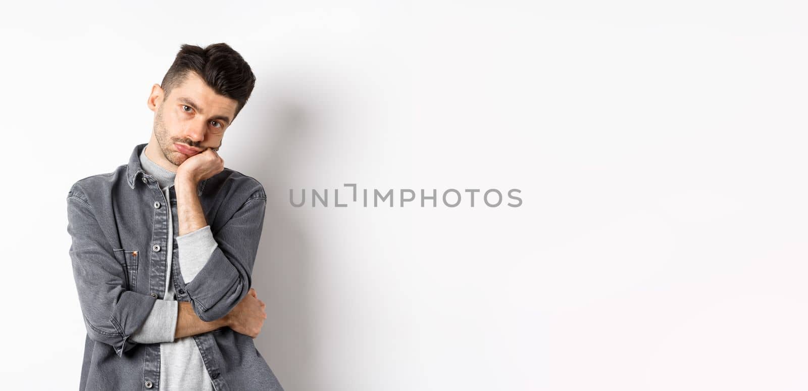 Bored and reluctant stylish guy look at camera without emotions, attend boring meeting, standing on white background.