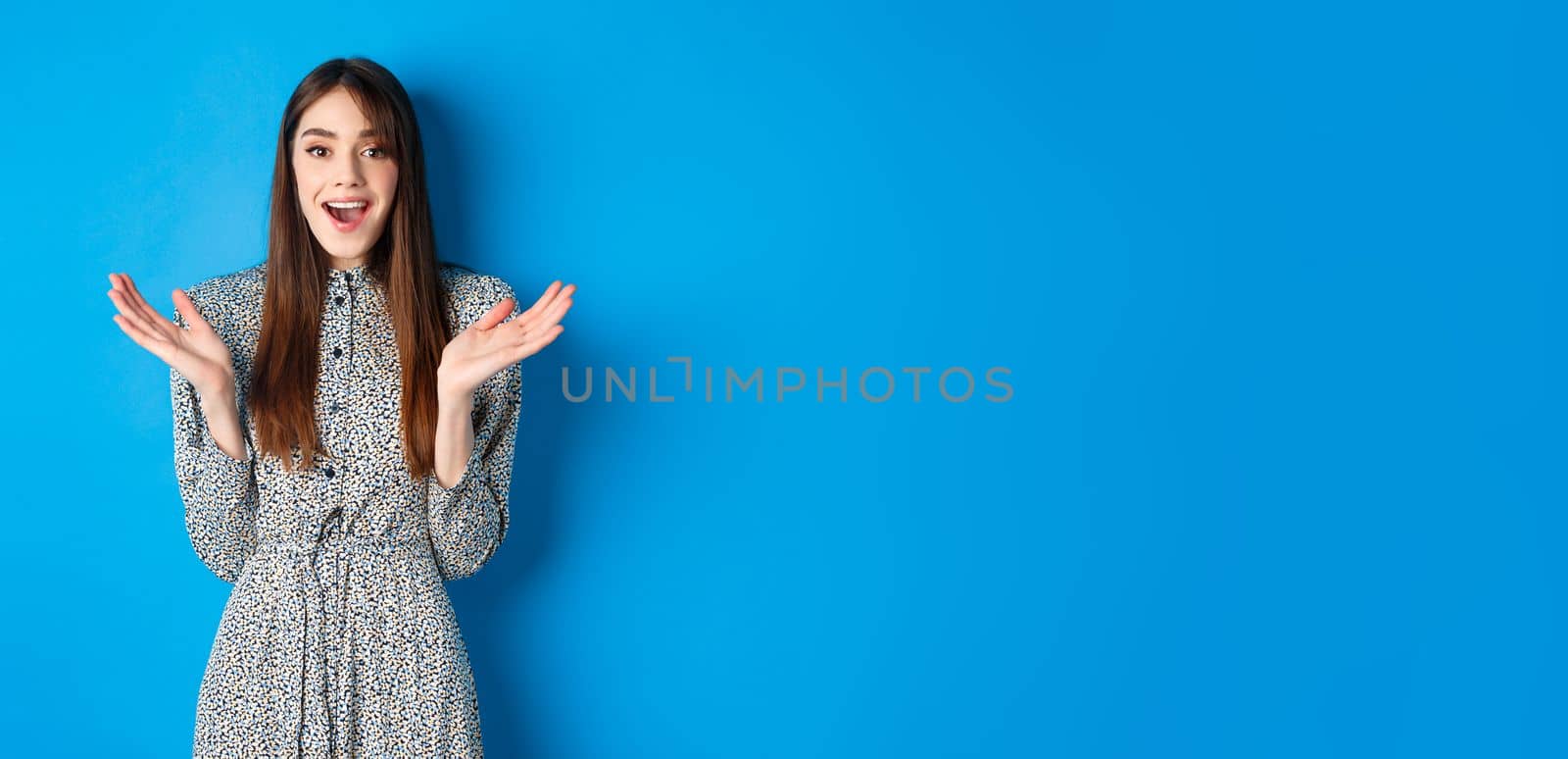 Excited beautiful woman clap hands and congratulate you, praising nice work, applause at camera and smiling, standing on blue background.