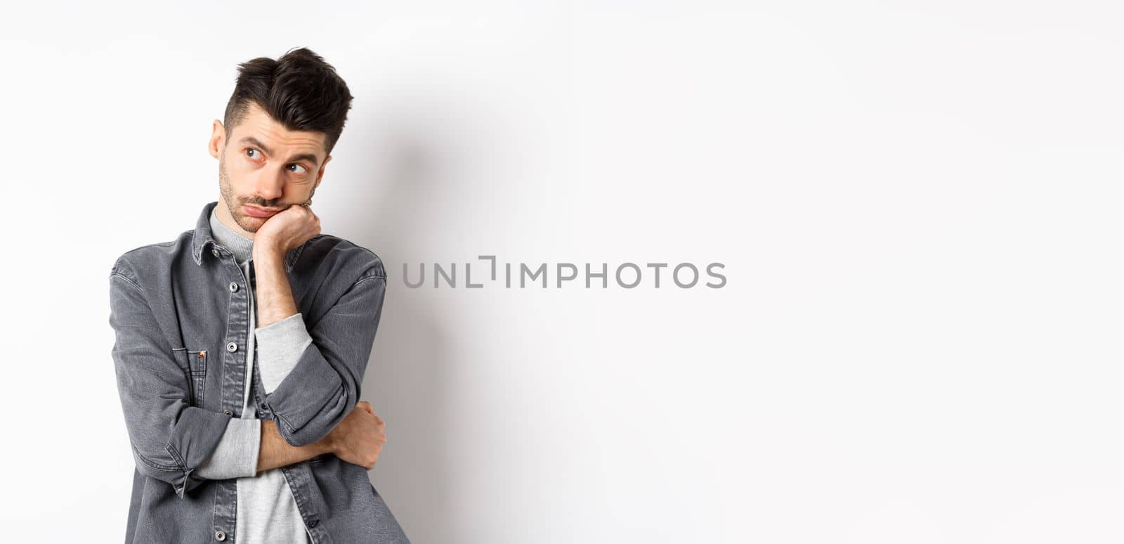 Gloomy thoughtful man looking aside, thinking or space out, staring at empty space bored, standing on white background.