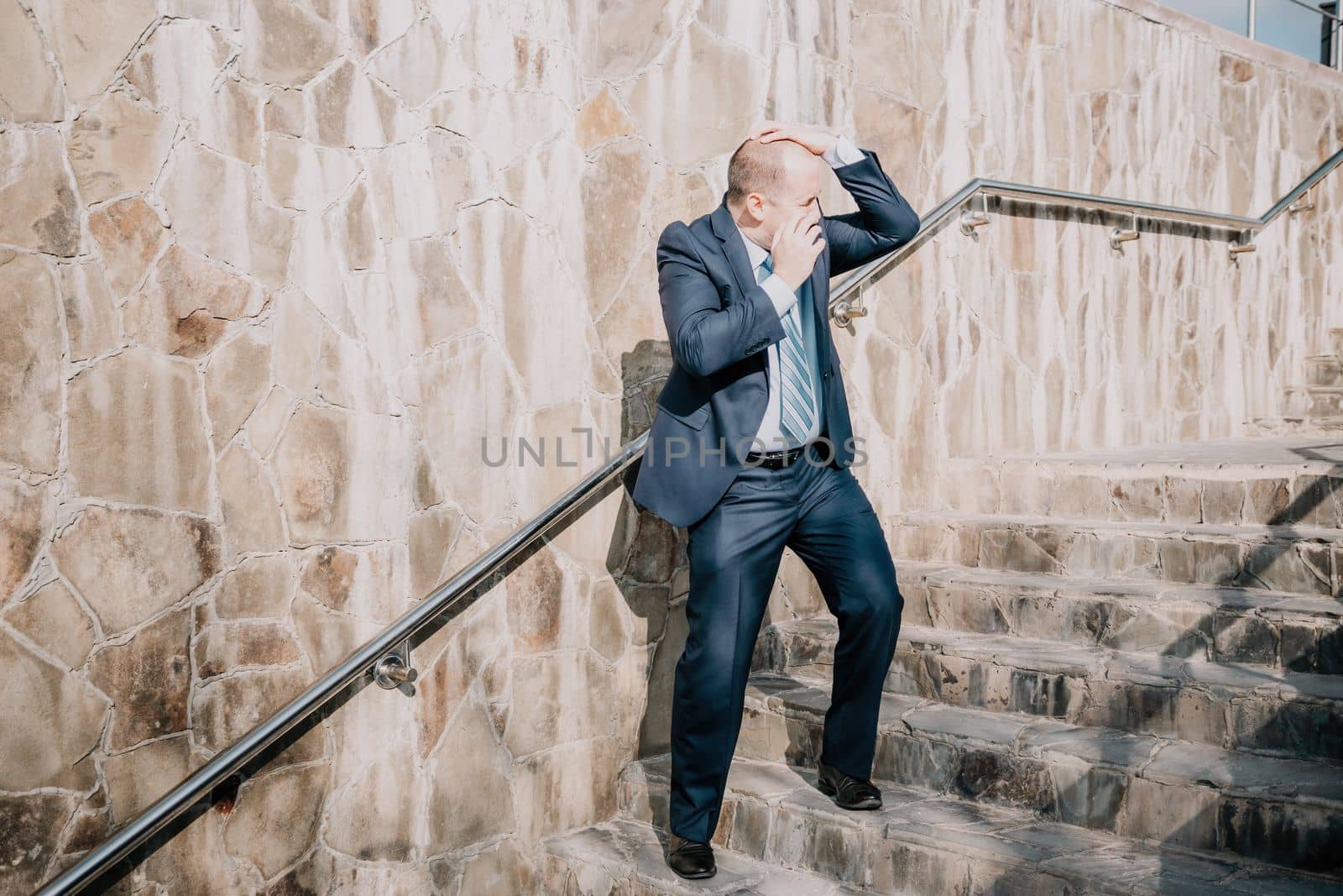 Portrait of a senior professional man in a suit with various problems. A middle-aged businessman with a briefcase descends the stairs.