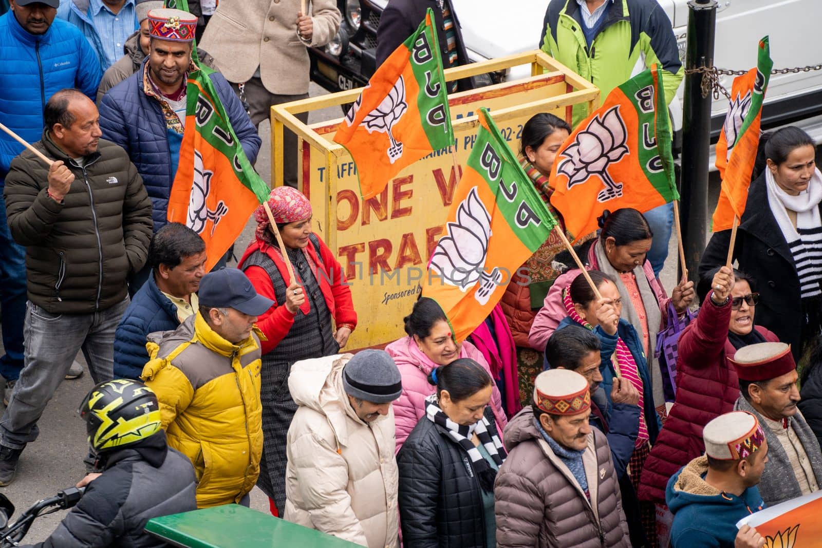 aerial drone shot crowd people with saffron flags of BJP protesting or celebrating victory in hill station manali standing in circle with leader by Shalinimathur