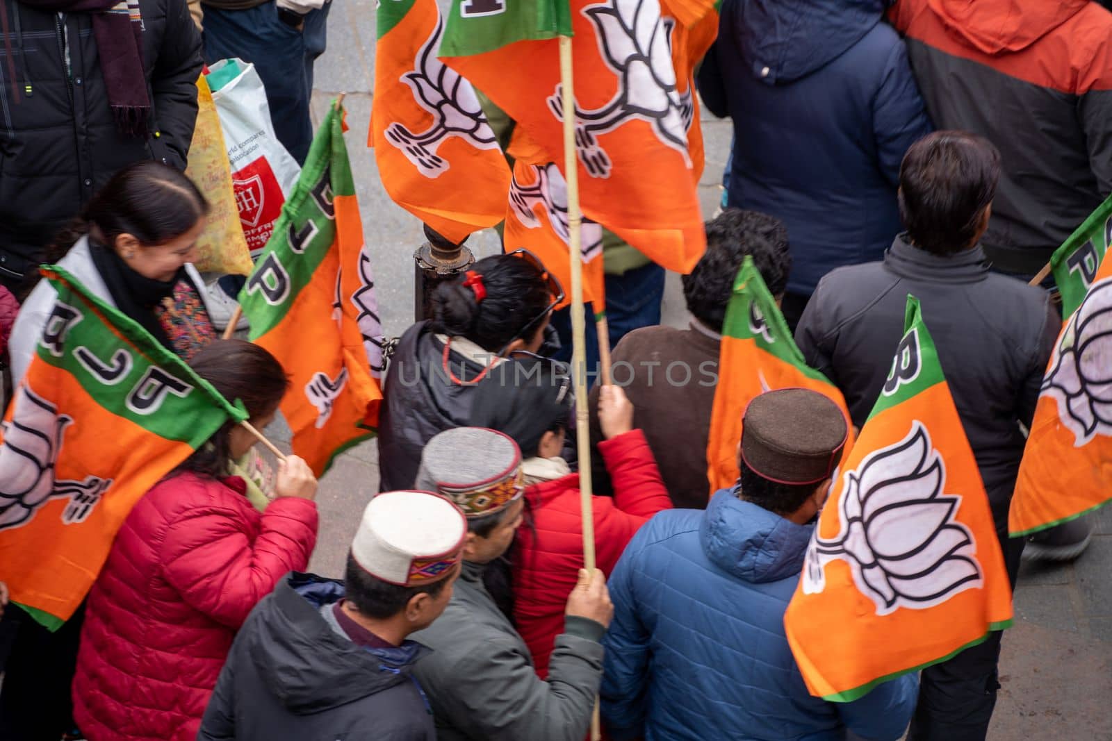 aerial drone shot crowd people with saffron flags of BJP protesting or celebrating victory in hill station manali standing in circle with leader by Shalinimathur