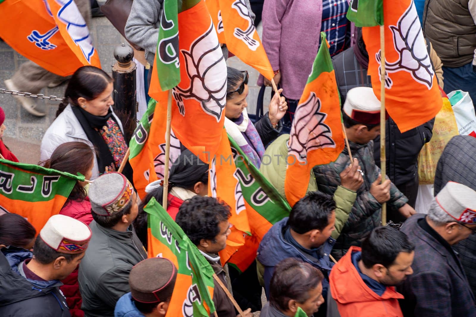 Delhi, India - circa 2022: aerial drone shot crowd people with saffron flags of BJP protesting or celebrating victory in hill station manali standing in circle with leader