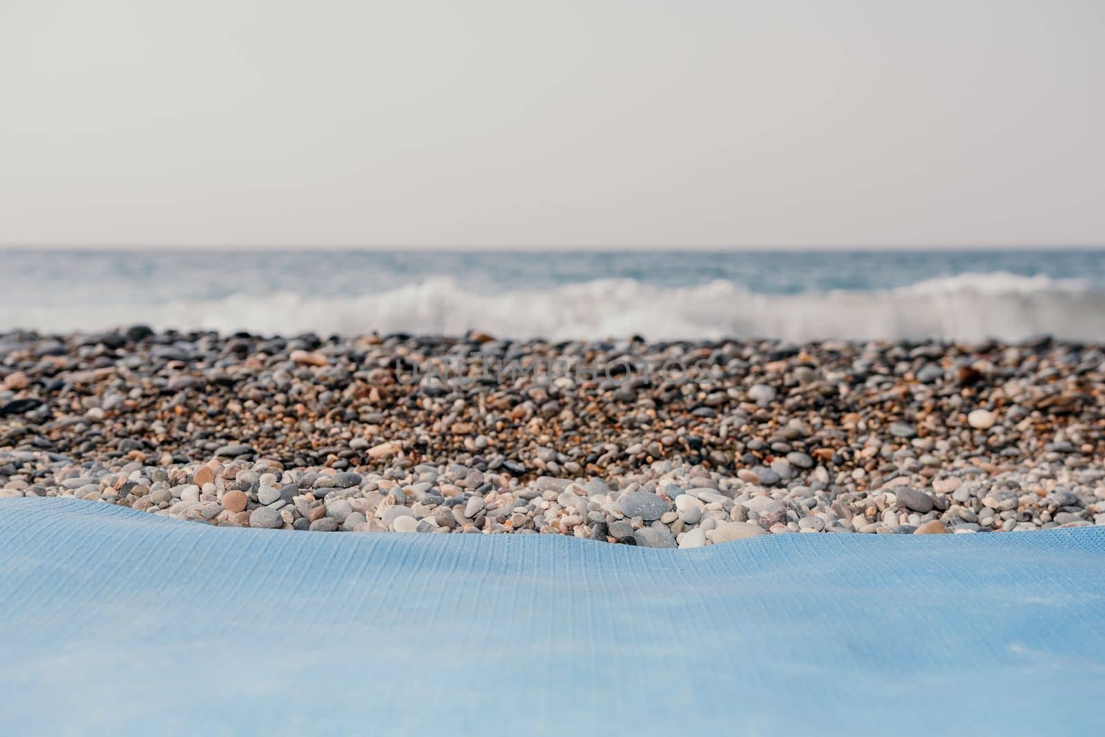 Blue yoga mat is on a sandy beach by the sea