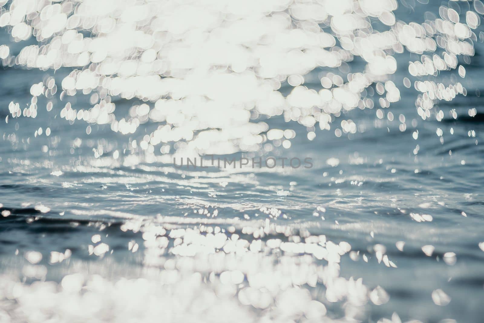 Abstract sea summer ocean sunset nature background. Sound of small waves on golden water surface in motion blur with golden bokeh lights from sun. Holiday, vacation and recreational concept.