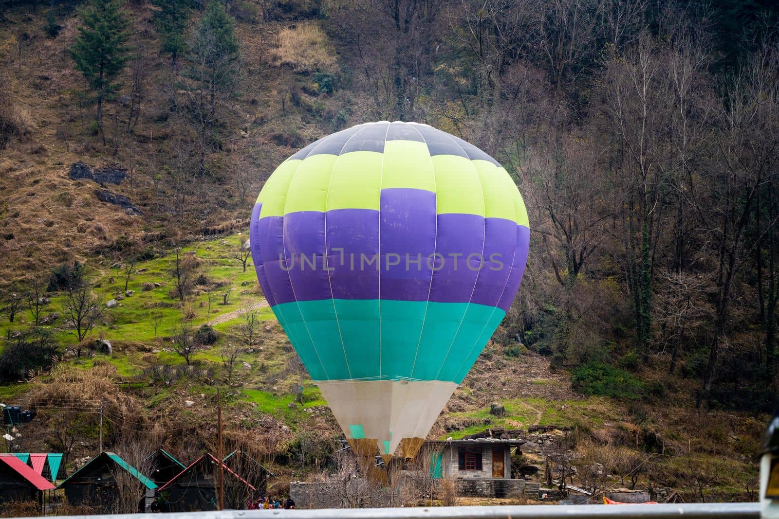 Hot air balloon with fire heating air in wicker basket with himalaya mountains in background showing this adventure in kullu manali valley by Shalinimathur