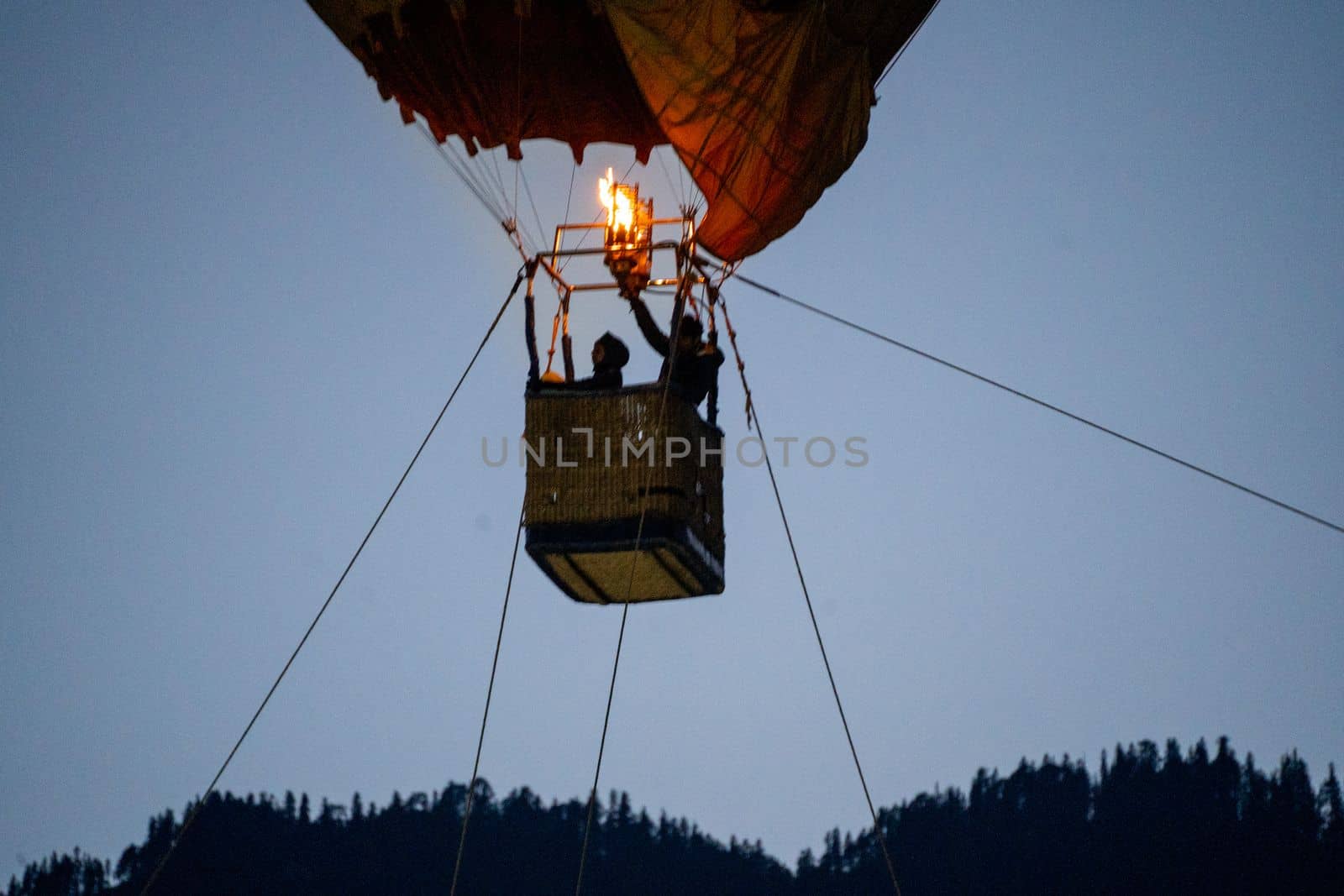 Close up shot of basket of Hot air balloon with fire heating air in wicker basket with himalaya mountains in background showing this adventure in kullu manali valley