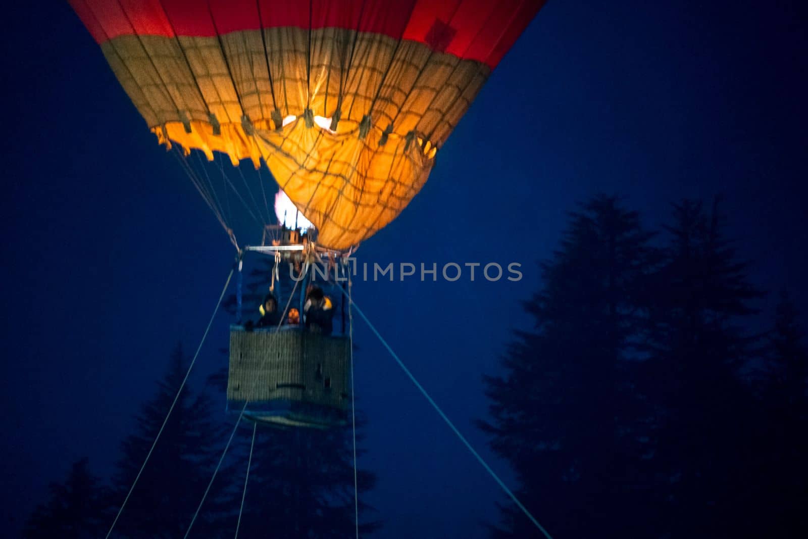 Close up shot of basket of Hot air balloon with fire heating air in wicker basket with himalaya mountains in background showing this adventure in kullu manali valley by Shalinimathur