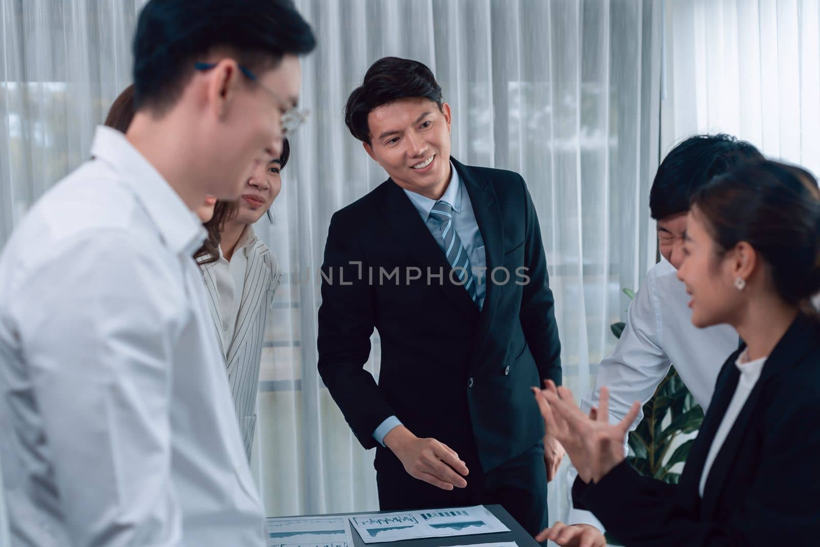 Harmony in office concept as business people analyzing dashboard paper together in workplace. Young colleagues give ideas at manager desk for discussion or strategy planning about project.