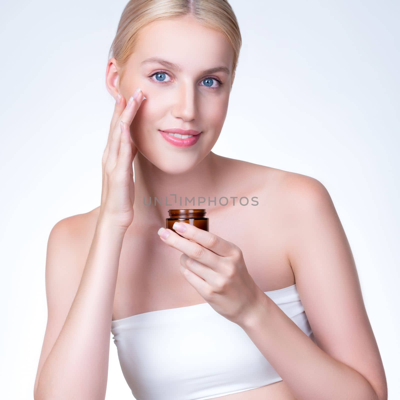 Closeup personable woman applying moisturizer cream on her face for perfect ski by biancoblue