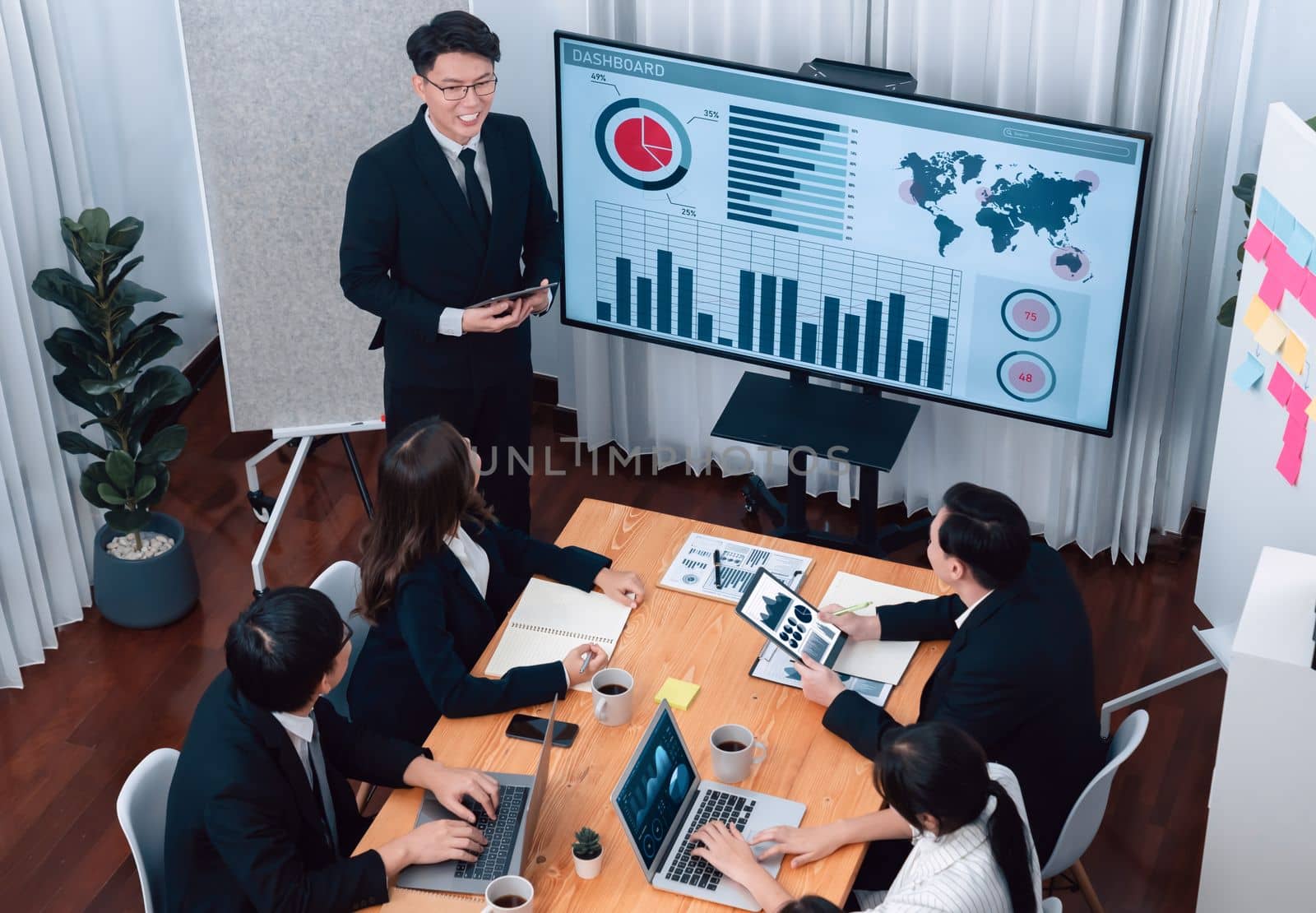 Confidence and asian businessman give presentation on financial analyzed by business intelligence in dashboard report to other people in board room meeting to promote harmony in workplace.