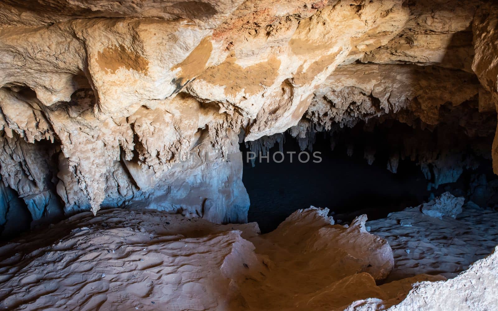 Inside interior of a large underground cave cavern with calcite stalactites hanging from the ceiling