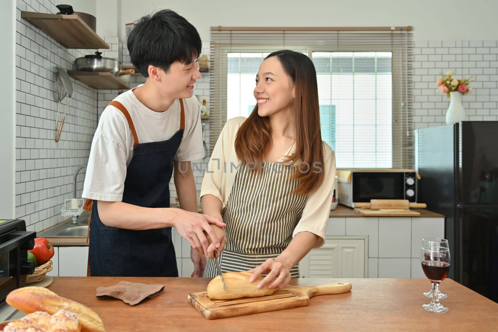 Joyful young couple preparing homemade pastry on wooden table in kitchen. Love, relationship, people and family by prathanchorruangsak
