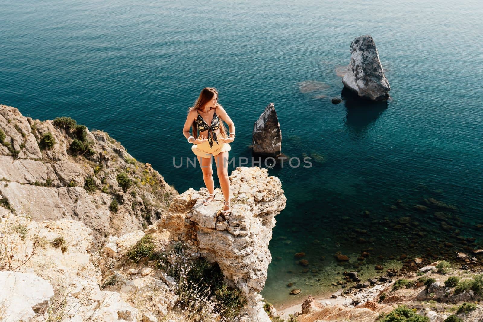 Woman travel sea. Happy tourist enjoy taking picture outdoors for memories. Woman traveler looks at the edge of the cliff on the sea bay of mountains, sharing travel adventure journey by panophotograph